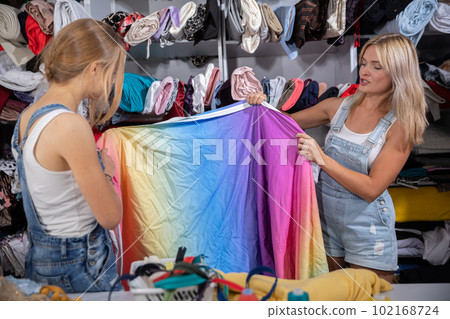 In the tailor's workshop, the designer and her assistant lay out the colorful fabric. In the tailor's workshop, the designer and her assistant lay out the colorful fabric. 102168724