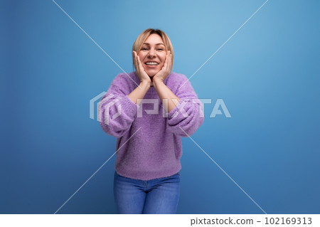 joyful energetic blond young woman consultant in purple sweater happy on blue background with copy 102169313