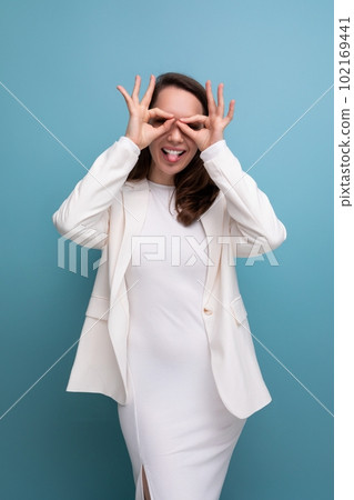 European pretty brunette young woman in a dress and jacket with a grimace 102169441