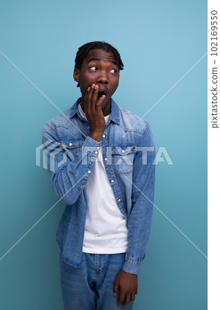 close-up portrait of a surprised young african guy with dreadlocks in a denim jacket 102169550