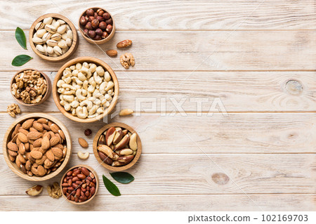 mixed nuts in wooden bowl. Mix of various nuts on colored background. pistachios, cashews, walnuts, hazelnuts, peanuts and brazil nuts 102169703