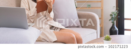 Lifestyle at home concept, Asian woman is taking notes on notebook while learning lesson online 102171223