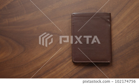Brown bespoke leather wallet on walnut wood table Brown bespoke leather wallet on walnut wood table 102174756