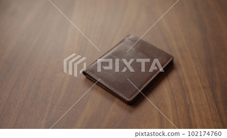 Brown bespoke leather wallet on walnut wood table Brown bespoke leather wallet on walnut wood table 102174760