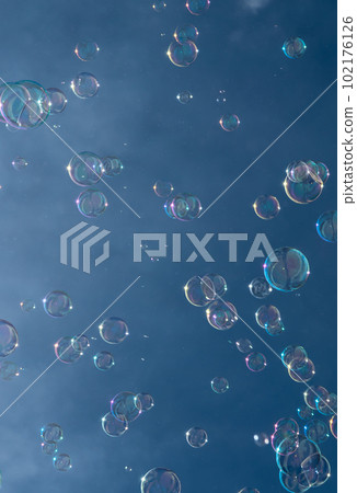 Numerous Colorful Soap Bubbles Float In Mid-Air In Front Of Blue Sky 102176126