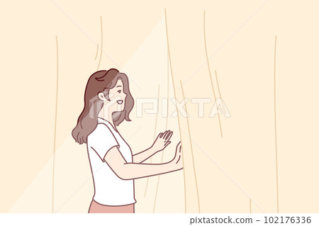 Smiling woman looks out window opening curtains and enjoying rays of summer morning sun Smiling woman looks out window opening curtains and enjoying rays of summer morning sun 102176336