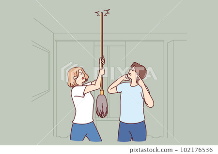 Young couple bangs on ceiling with mop urging neighbors to stop party or turn off loud music 102176536