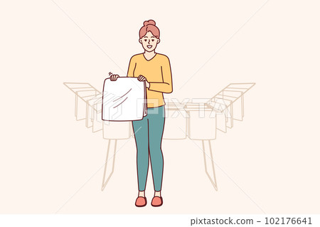 Woman housewife stands near dryer with clean towels doing household chores to create comfort 102176641