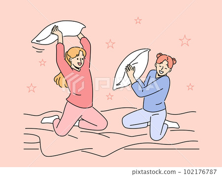 Smiling girls engaged in pillow fight at home Smiling girls engaged in pillow fight at home 102176787