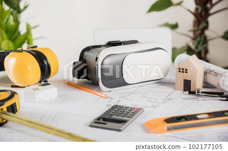 Architect workplace top view. Architectural blueprint paper project plans on desk table, tool for engineer contractor building design working drawing and VR glasses, industry virtual technology Architect workplace top view. Architectural blueprint paper project plans on desk table, tool for engineer contractor building design working drawing and VR glasses, industry virtual technology 102177105