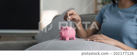 Woman hands hold a pink piggy bank and puts a coin there. The concept of saving money or savings, investment Woman hands hold a pink piggy bank and puts a coin there. The concept of saving money or savings, investment 102177126