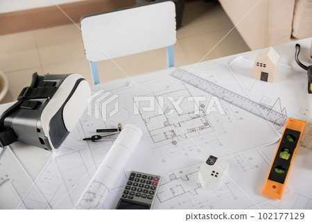 Architectural blueprint paper project plans on desk table, tool for engineer contractor building interior design drawing and VR glasses, industry virtual technology, Architect workplace concept Architectural blueprint paper project plans on desk table, tool for engineer contractor building interior design drawing and VR glasses, industry virtual technology, Architect workplace concept 102177129