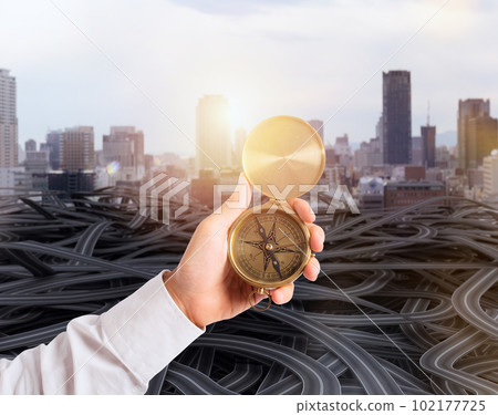 Businessman holds a compass to help himself to find the correct way 102177725