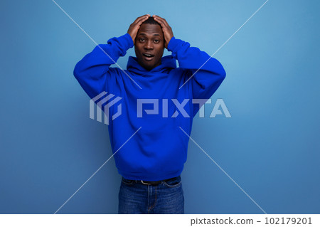 close-up of an upset black american man in a sweatshirt with a hood on a studio background with copy 102179201