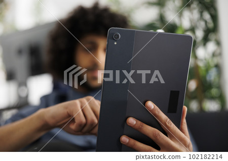 Arab business entrepreneur holding digital tablet while working in start up office. Company young man marketing manager chatting online and searching information on internet 102182214