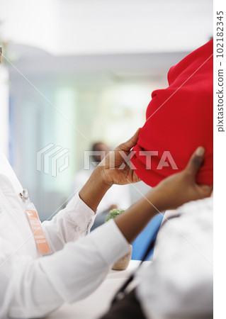 African american woman hands dressing mannequin to showcase fashion brand new collection in boutique. Store assistant arms changing clothes on display dummy model in shopping mall 102182345