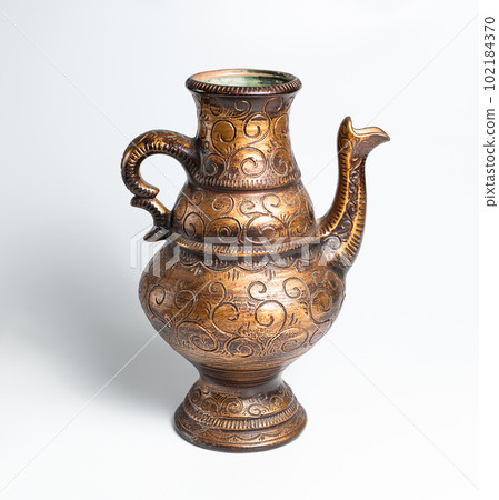 Copper object old Jug. Handcraft Decorative interior. Ancient Style. White background. Art. Stock photo. Selective focus. Copper object old Jug. Handcraft Decorative interior. Ancient Style. White background. Art. Stock photo. Selective focus. 102184370