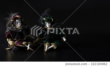 Porcelain doll, realistic vintage toys with grey eyes. The dolls are dressed in a carnival outfit, decorated with gold, harlequin, space for text Porcelain doll, realistic vintage toys with grey eyes. The dolls are dressed in a carnival outfit, decorated with gold, harlequin, space for text 102184862