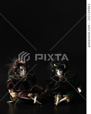 Porcelain doll, realistic vintage toys with grey eyes. The dolls are dressed in a carnival outfit, decorated with gold, harlequin, space for text Porcelain doll, realistic vintage toys with grey eyes. The dolls are dressed in a carnival outfit, decorated with gold, harlequin, space for text 102184863