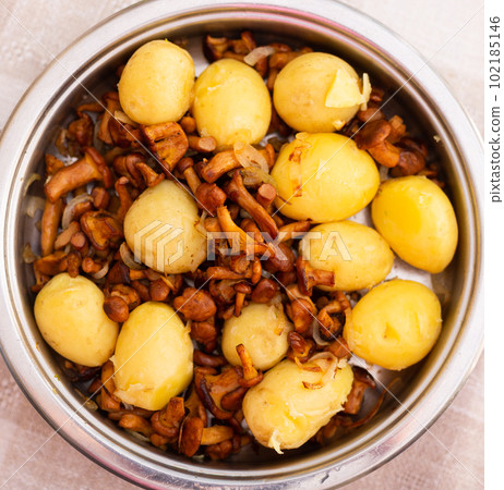 appetizing fried chanterelle mushrooms with new potatoes in skillet. top view appetizing fried chanterelle mushrooms with new potatoes in skillet. top view 102185146