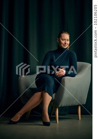 Happy, smiling, beautiful young business woman, psychologist in elegant dress sitting on armchair in her office Happy, smiling, beautiful young business woman, psychologist in elegant dress sitting on armchair in her office 102186205
