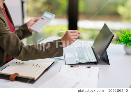 Concept of business office woman working,Closeup businesswoman checking her invesment plan with analyzing document and business investment graph data by using calculator and laptop 102186240