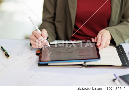 Concept of business office woman working,Closeup businesswoman checking her invesment plan with analyzing document and business investment graph data by using calculator and laptop 102186241