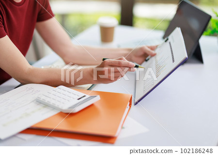 Concept of business office woman working,Closeup businesswoman checking her invesment plan with analyzing document and business investment graph data by using calculator and laptop 102186248