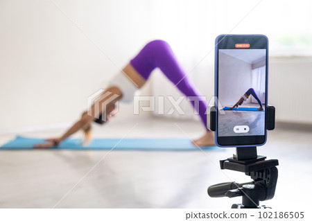 woman practicing yoga poses stretching in front of phone camera sport blogger teacher yoga online class wellness coach 102186505
