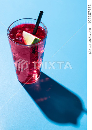 Cape Codder cocktail with vodka, cranberry juice and lime on blue background Cape Codder cocktail with vodka, cranberry juice and lime on blue background 102187481