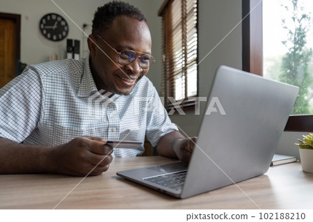 Black man holding credit card for online shopping and payment makes a purchase on the Internet, Online payment, Business financial and technology Black man holding credit card for online shopping and payment makes a purchase on the Internet, Online payment, Business financial and technology 102188210