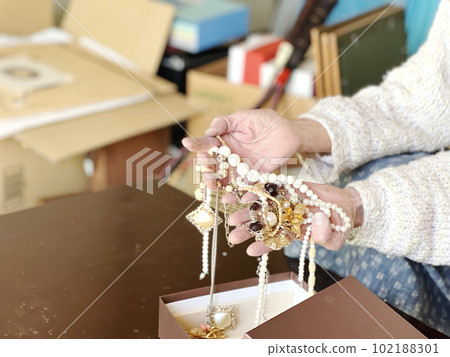 Elderly woman's hand taking out jewelry from a box during decluttering 102188301