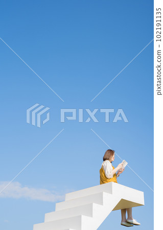 asian woman relax and reading on white stair in flower garden on springtime vacation asian woman relax and reading on white stair in flower garden on springtime vacation 102191135