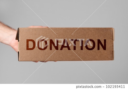 Donation box in hand. Volunteer donating smth, necessities for needy, poor. Help, charitable aid concept Donation box in hand. Volunteer donating smth, necessities for needy, poor. Help, charitable aid concept 102193411
