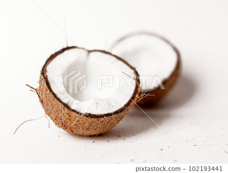 Open coconut halves. Two parts pieces of coco nut fruit with brown shell, ripe flesh 102193441