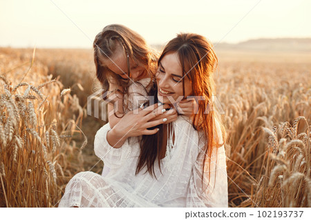 Family in a summer field. Sensual photo. Cute little girl. Woman in a white dress. 102193737