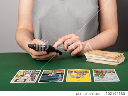 Lodz, Poland March 31 2023 Tarot card reader searching arcana spread meaning online in internet using mobile phone, smartphone, telling, reading taro. Modern fortune teller 102194680