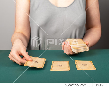 Lodz Poland April 15 2023 Tarot reader, fortune teller spreading three taro cards on green table for fortune telling 102194690