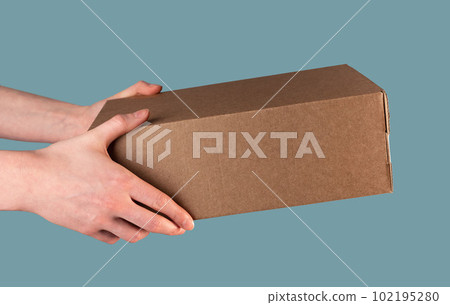 Hand holding, giving brown kraft cardboard box. Receiving carton package, post order of rectangle shape 102195280