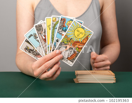 Lodz, Poland April 07 2023 Fortune teller showing tarot cards, arcanas in hand, reading, telling future. Cartomancy, divination concept 102195363