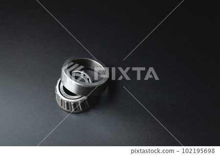 Tapered roller bearing close-up with copy space for your text. Spare mechanical part on a black background. 102195698