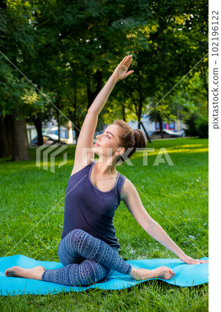 Young woman doing yoga exercises in the summer city park. Young woman doing yoga exercises in the summer city park. 102196122