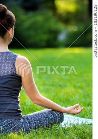 Young woman doing yoga exercises in the summer city park. 102196128