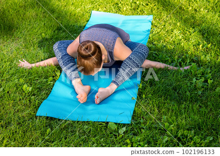 Young woman doing yoga exercises in the summer city park. 102196133