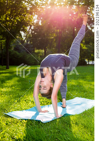 Young woman doing yoga exercises in the summer city park. 102196134