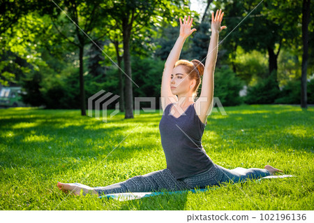 Young woman doing yoga exercises in the summer city park. 102196136