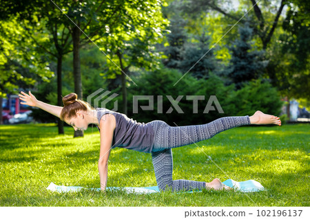 Young woman doing yoga exercises in the summer city park. 102196137