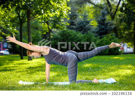 Young woman doing yoga exercises in the summer city park. 102196138