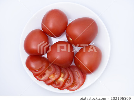Red tomatoes on a white plate. Sliced tomatoes on a white background. Vegetables on a plate. Red tomatoes on a white plate. Sliced tomatoes on a white background. Vegetables on a plate. 102196509