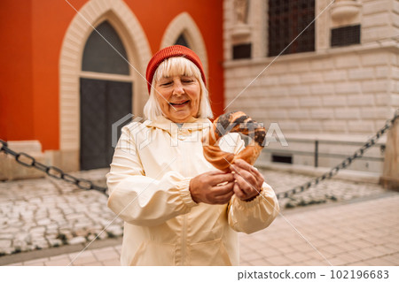 Senior woman holding prezel, traditional polish snack on the Market square in Krakow Senior woman holding prezel, traditional polish snack on the Market square in Krakow 102196683